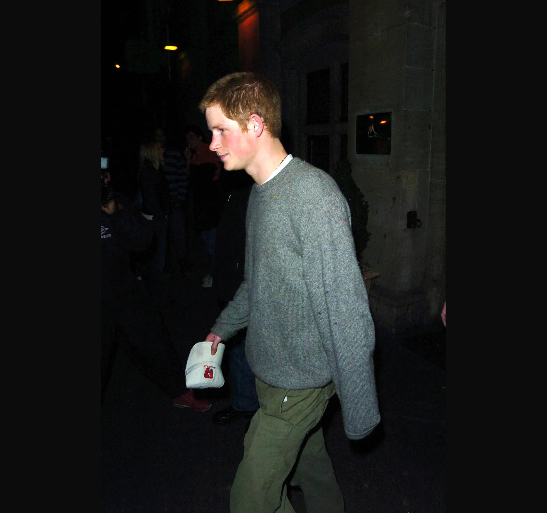 Harry in the same grey jumper and khaki trousers, something white in his hand.