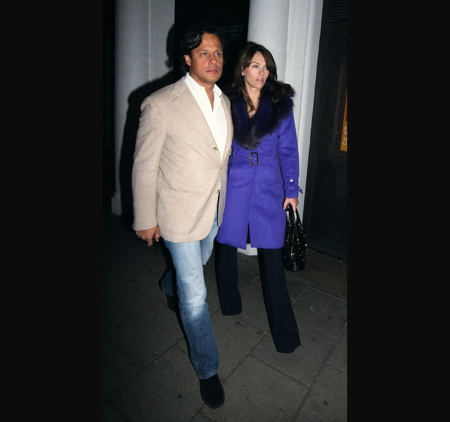 NOBU BERKELEY ST, MARCH 2006. Elizabeth Hurley and businessman Arun Nayar leave Nobu Berkeley St restaurant in Mayfair on the night of 1 March 2006.

She wears a violet coat with a dark fur collar and black flared trousers, and carries a black handbag. He is in a beige jacket, a white open neck shirt and light jeans.