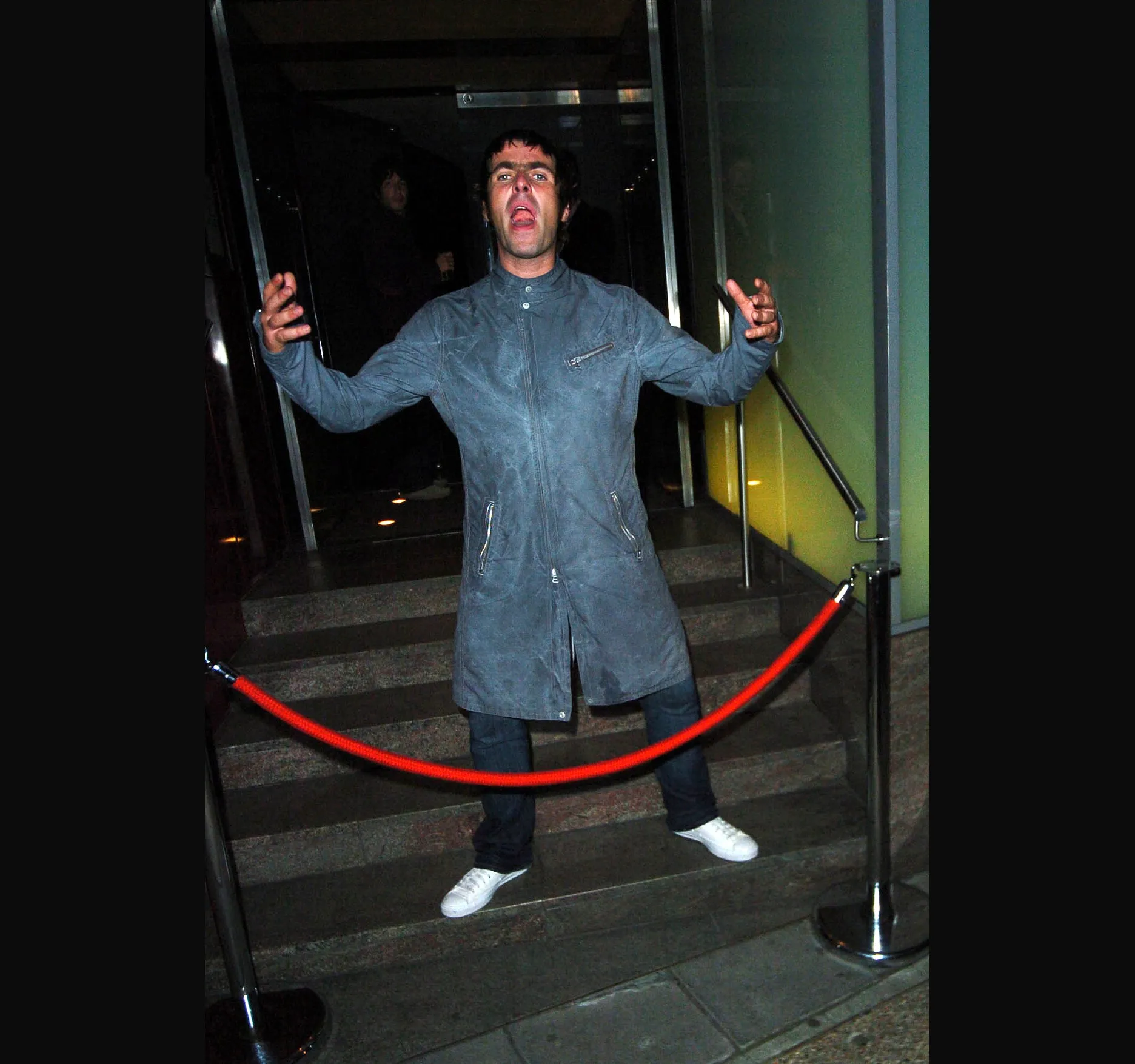 Arms held out and mouth open, still behind the rope.