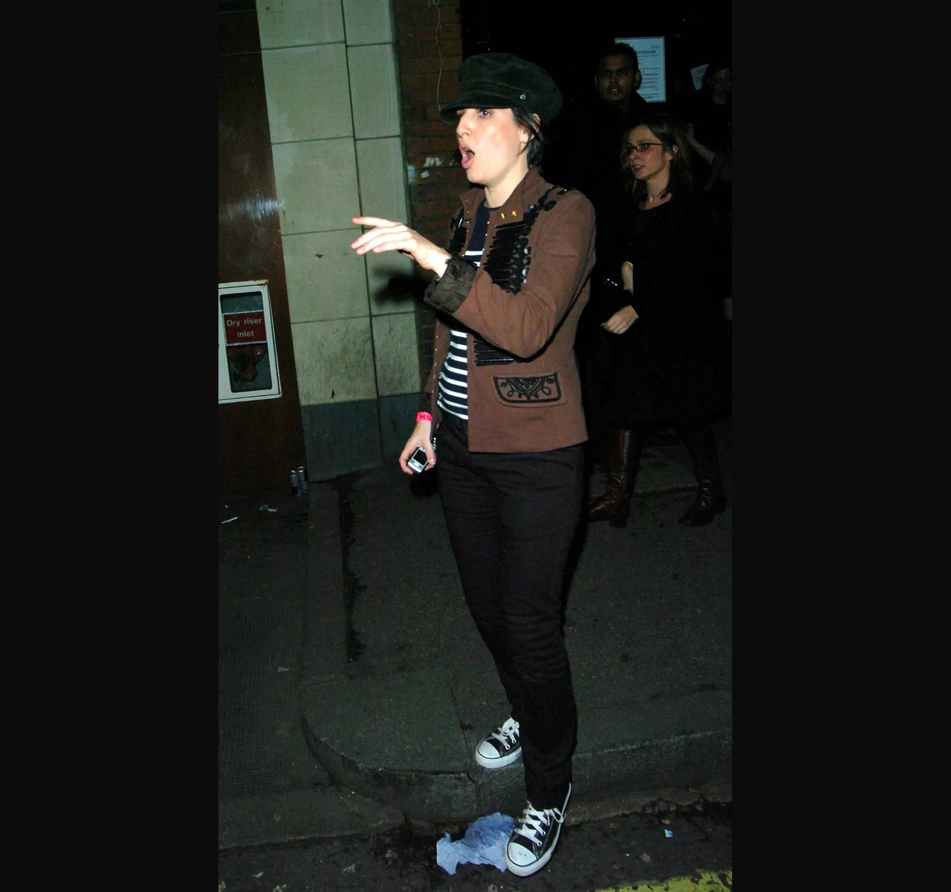 Texas singer Sharleen Spiteri, in a flat cap, brown jacket and trainers, gestures as she leaves.