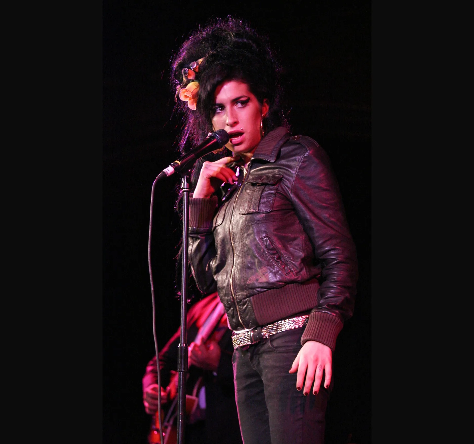One hand up near the microphone as she leans into a line.