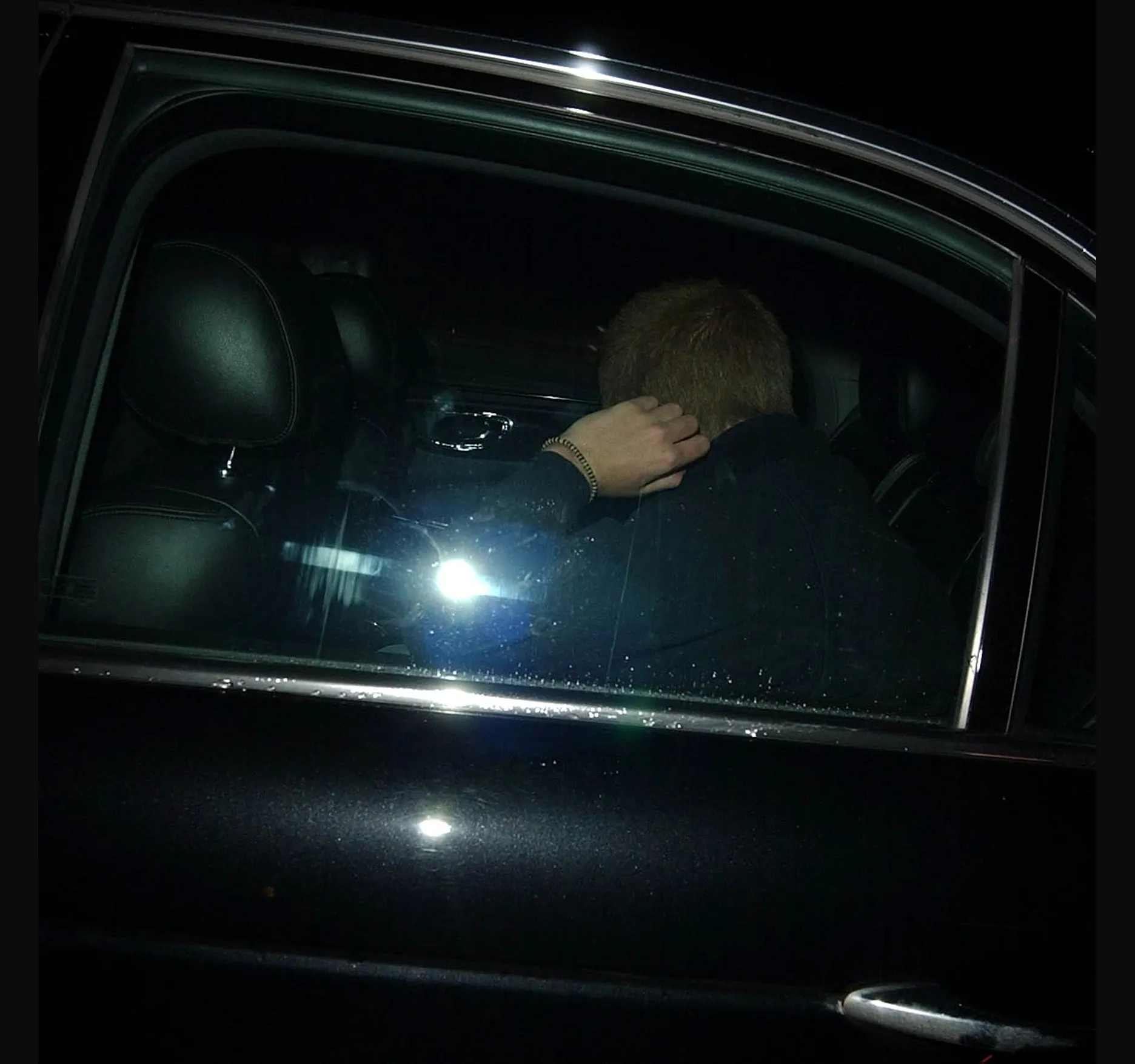 Inside the car, a hand to the head, as it pulls away.