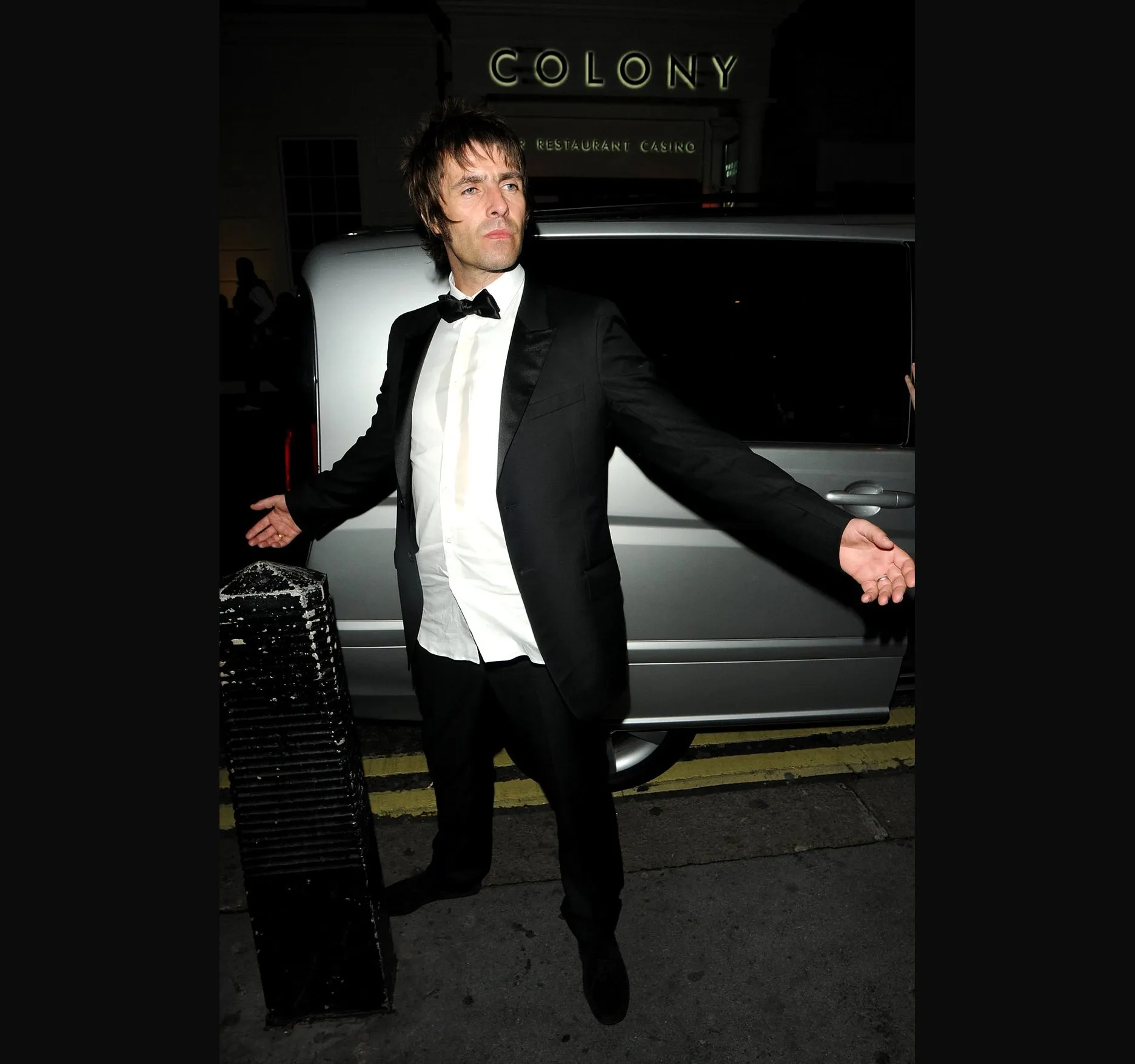 The usual arms-wide pose in front of a silver van.