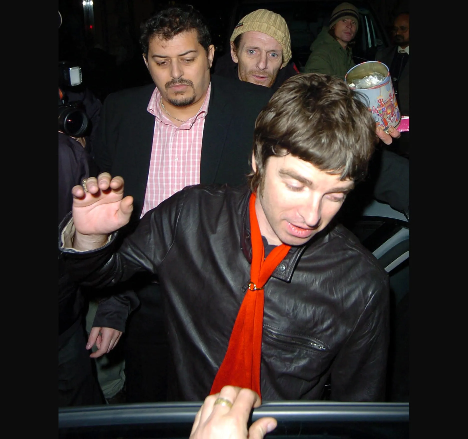 Eyes down and a wave of the hand as Noel reaches the car door, with photographers close behind.