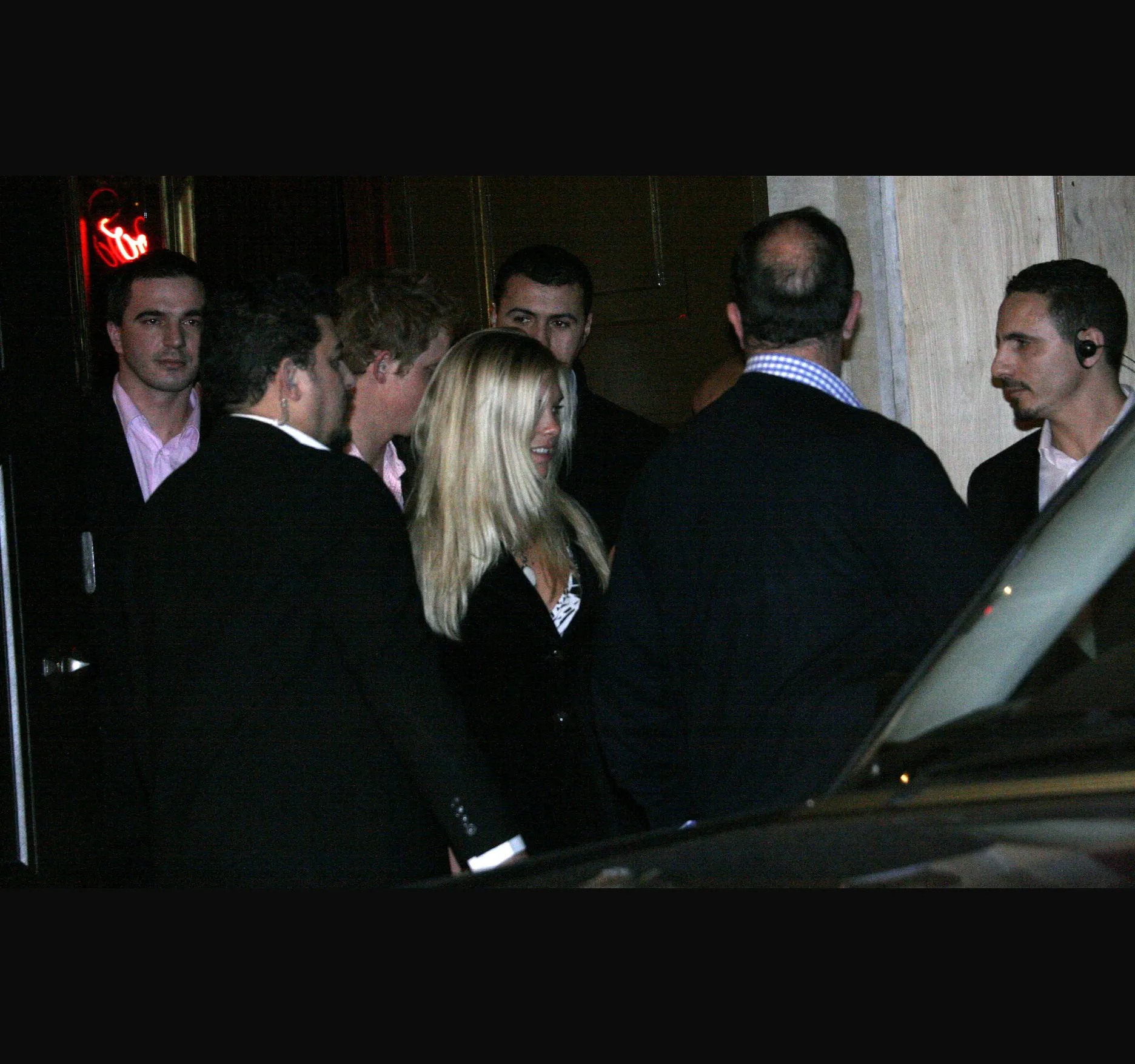 Chelsy Davy, in the middle with long blonde hair, and Harry just behind her as the group moves towards the car.