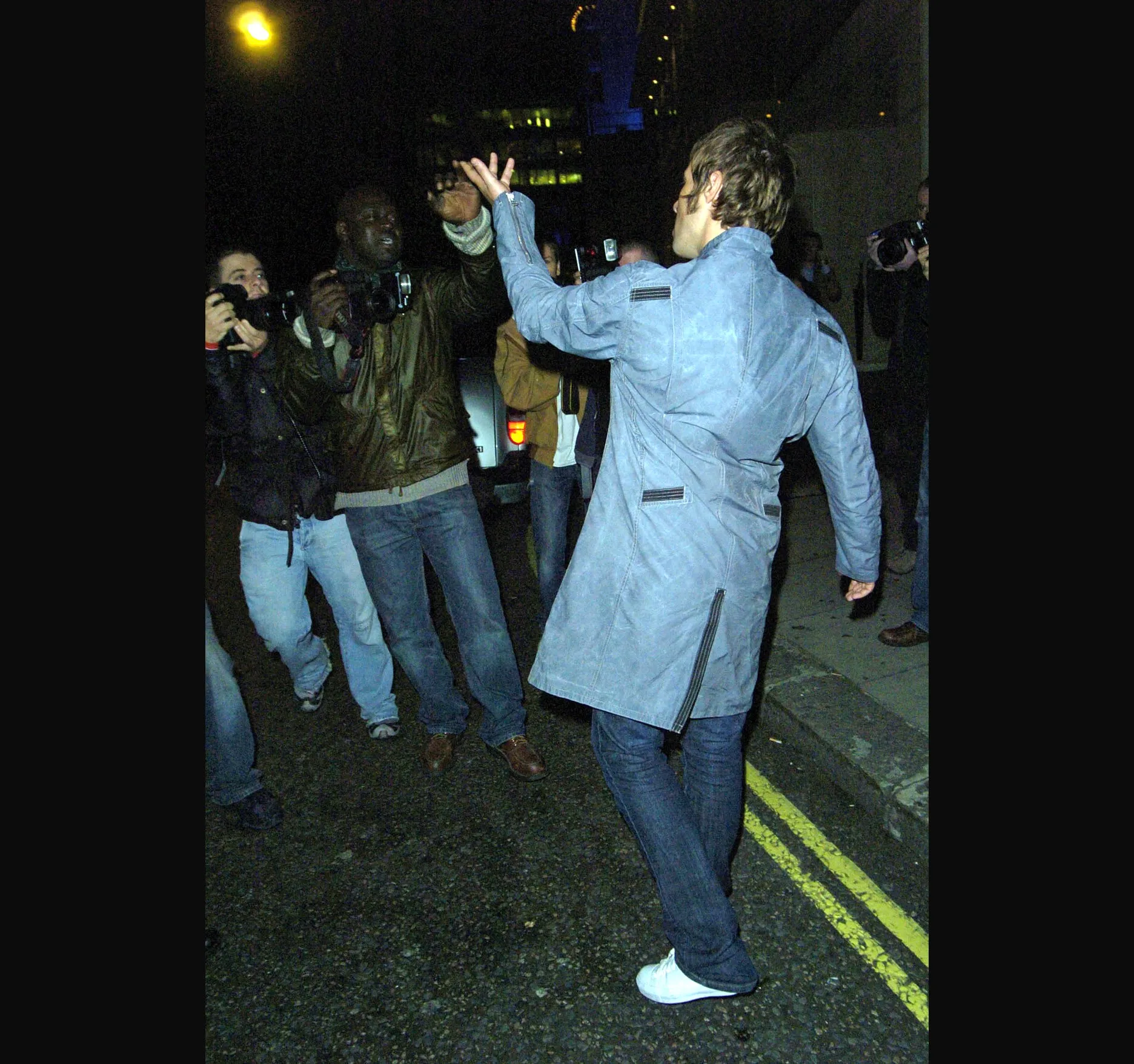 One arm raised as he moves off down the street.