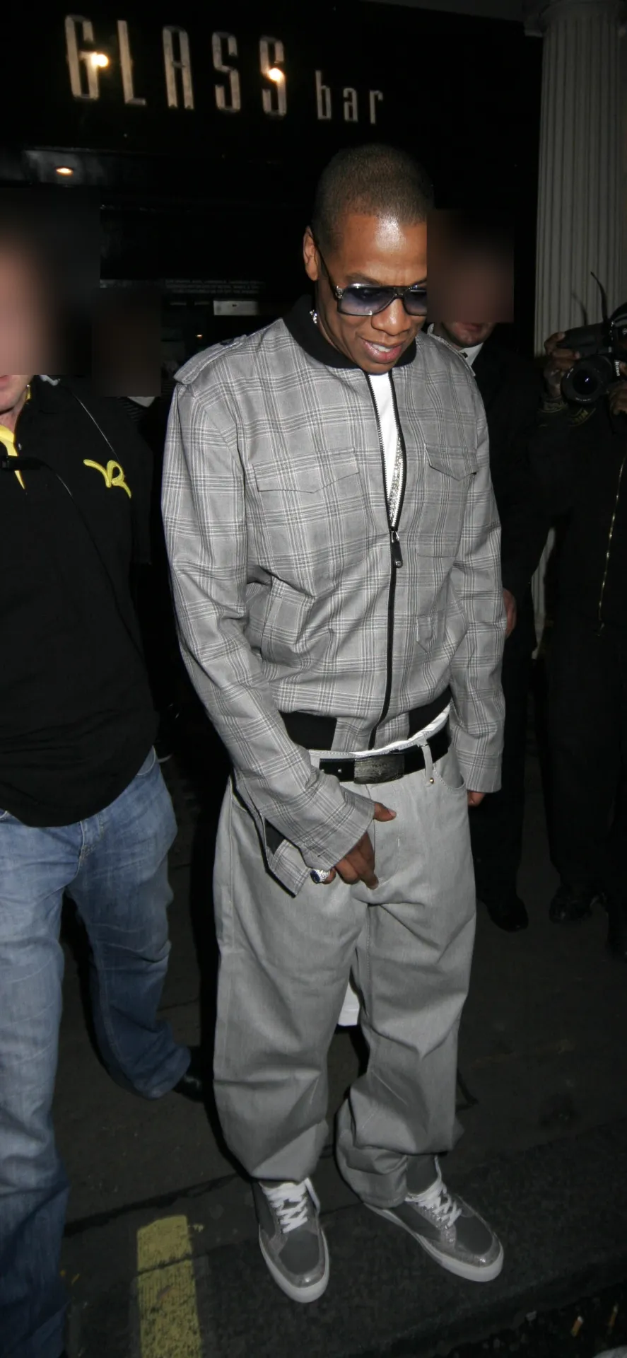 Jay-Z in a grey check jacket and sunglasses leaving a London club at night.