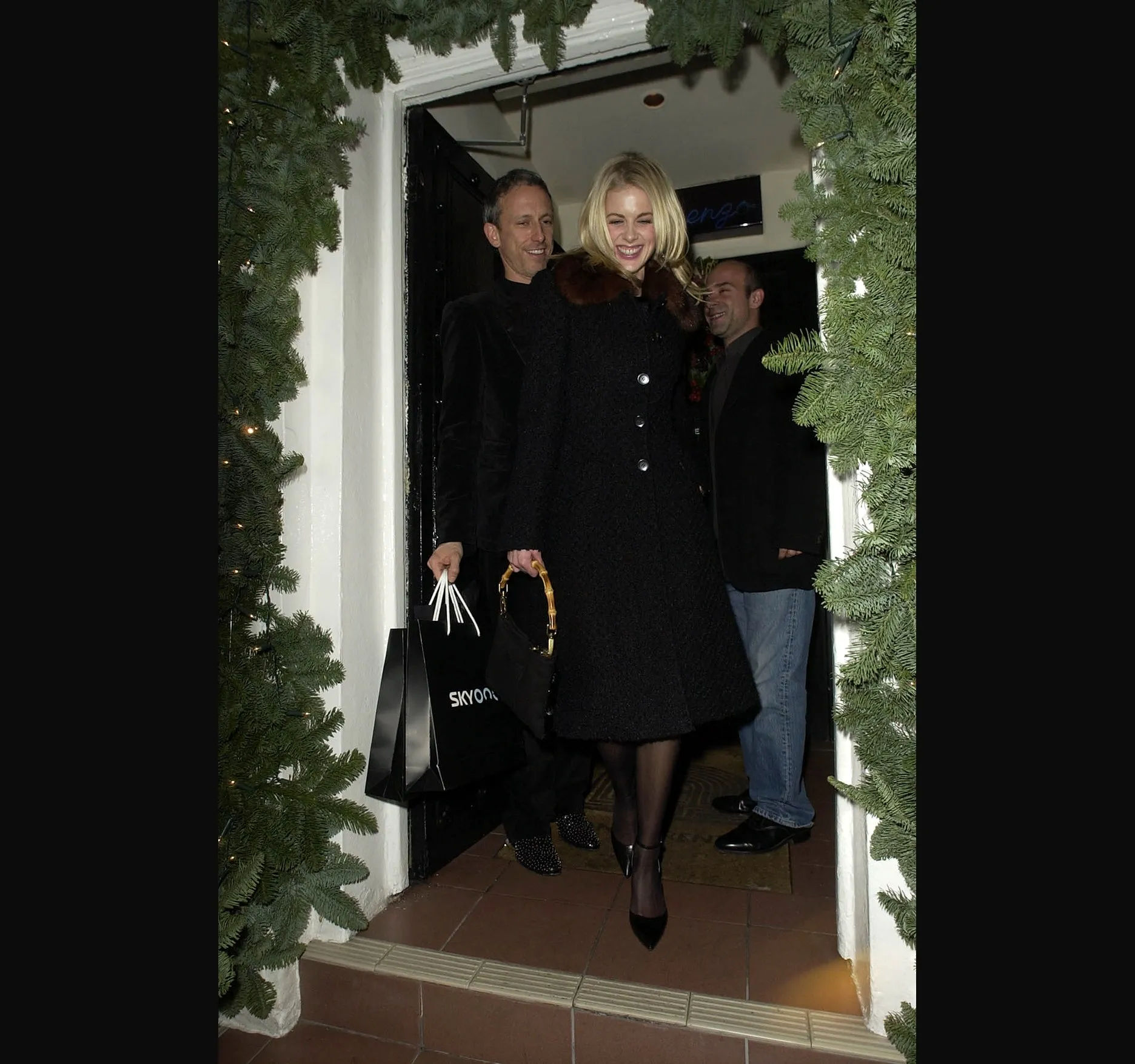 DONNA AIR. Presenter Donna Air laughs as she steps out of the San Lorenzo doorway in a black coat with a dark fur collar.